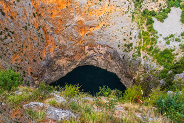 Red lake is a limestone crater, with it's cliffs 200 m high and lake 300 m deep. Imotski, Croatia, august 2020