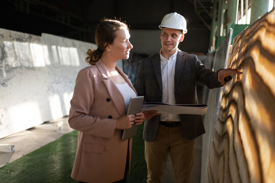 Professional manager consulting female architect in stone warehouse