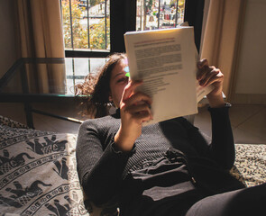 woman reading and underlining a book on the sofa