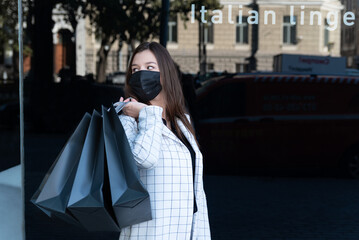 Shopping during quarantine. Girl with paper shopping bags and protective mask. Black Friday