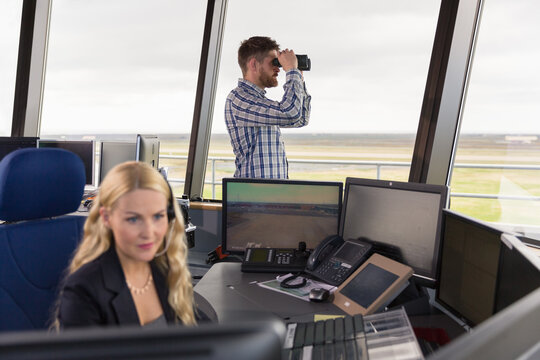 Bearded dispatcher watching airfield through binoculars