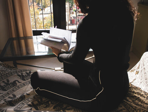 woman reading and underlining a book on the sofa