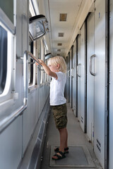 Fototapeta na wymiar Sad boy with interest looks in the window of the train. Traveling with children