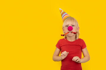 Boy in party hat, clown nose, and whistle. Childrens holiday party.