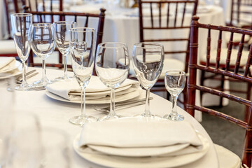 Fancy table set for dinner with napkin glasses in restaurant, luxury interior background. Wedding elegant banquet decoration and items for food arranged by catering service on white tablecloth table.