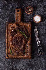 Grilled beef steak with spices on a wooden board.