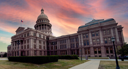 View of the Texas State Capitol building with domed roof made of Sunset Red Granite stone at dusk with pink and orange colored sky