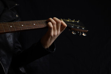 musician with a guitar on a black background in a leather jacket
