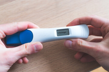 Woman checking pregnancy test. Result positive, “Schwanger”