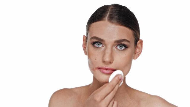 Young adult woman with cotton pad removing lipstick smudge isolated on white
