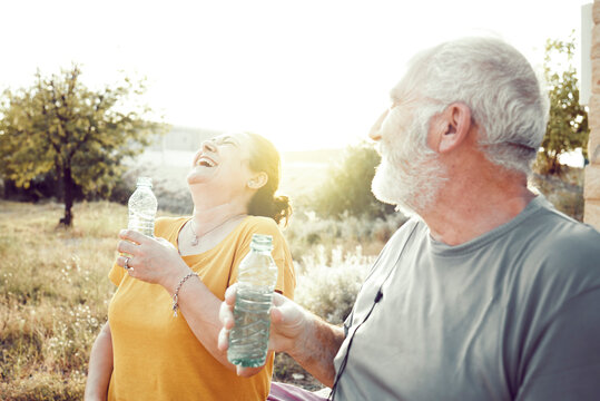 An older couple laughs while resting to drink water