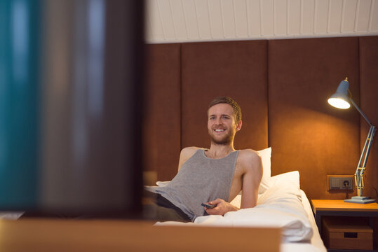 Happy man watching TV on bed