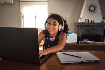 a girl smiling as she studies with her laptop from home