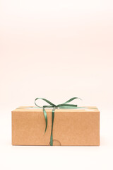 Vertical photo of a box of kraft paper tied with a green ribbon on a white background