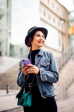 Beautiful woman in autumn dress with hat using cell phone