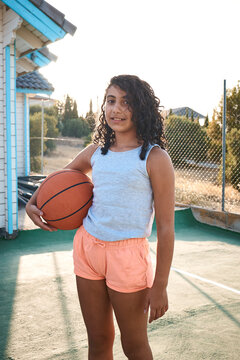 A little girl with a basket ball with the sunset in the background