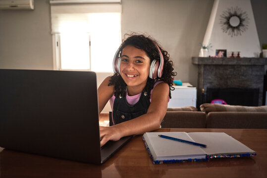 a girl smiling as she studies with her laptop from home