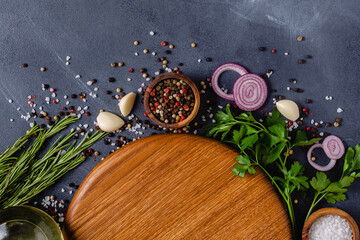 Herbs and condiments on black stone background.