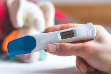 Woman checking pregnancy test. Result positive, “Schwanger”