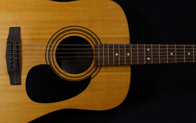 Classic wooden acoustic guitar closeup, on a black background, rock, country music concept