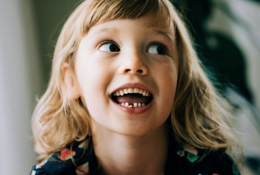 young girl smiling showing her wobbly tooth looking happy