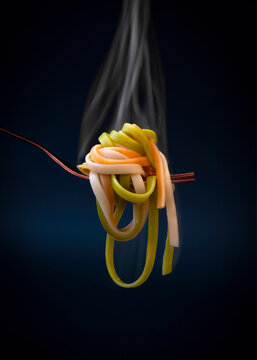 Tasty hot pasta on fork in studio