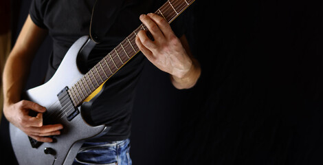 Fototapeta na wymiar musician plays electric guitar, concept of rock, metal music on black background