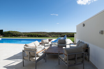 patio seating area in the garden of a luxury holiday villa with swimming pool in the background