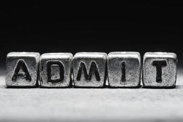 Admit concept. The inscription on metal 3D cubes isolated on a black background, grunge style