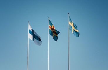 3 skandinavian flags flying together against a blue sky in Finland