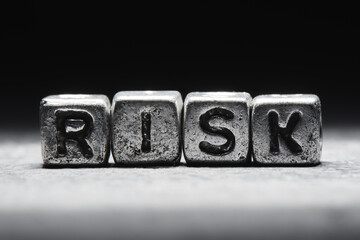 Risk concept. The inscription on metal 3D cubes isolated on a black background, grunge style