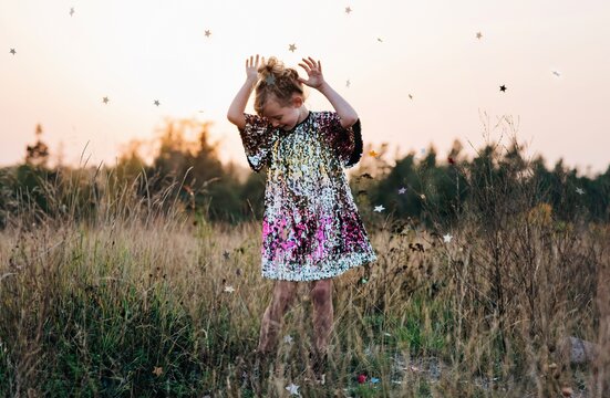 little girl dancing in a sparkly dress with star confetti falling