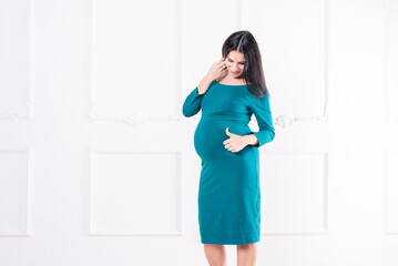 A pregnant girl in a dress with a big belly.