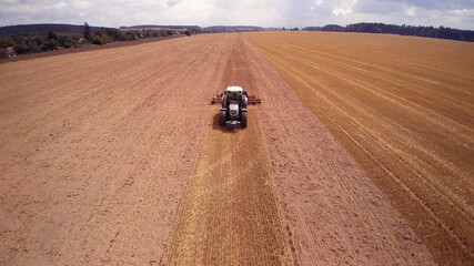agricultural tractor with plows. while plowing large field.