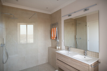 En suite bathroom with large tiled shower and double sink with mirror