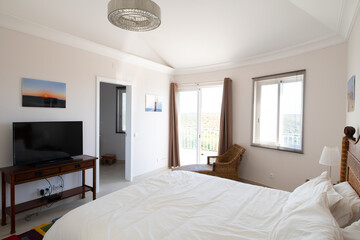 Master bedroom with wooden furniture, white bedding and sliding doors to terrace in a renovated holiday villa