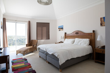 Master bedroom with wooden furniture, white bedding and sliding doors to terrace in a renovated holiday villa