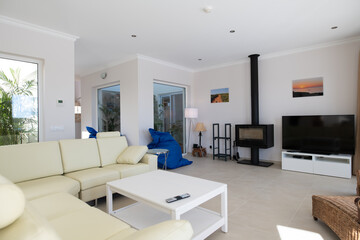 Fototapeta na wymiar Modern, clean living room of luxury family house with large l-shape leather sofa and tiled floors