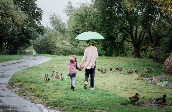 mother and daughter walking together holding hands on a rainy day