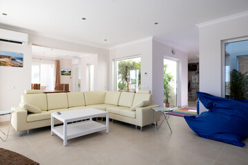 Modern, clean living room of luxury family house with large l-shape leather sofa and tiled floors