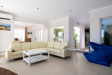 Fototapeta premium Modern, clean living room of luxury family house with large l-shape leather sofa and tiled floors