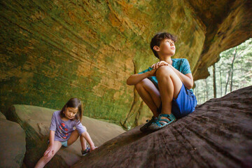 Two children play together on a rocky outcrop in a sandstone gorge