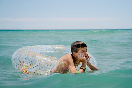boring white boy swimming in a float in turquoise mediterranean sea