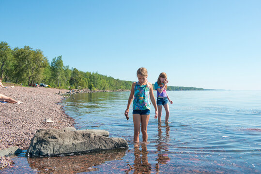 Two Young Girls Exploring Rocky Shoreline