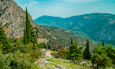 Fototapeta premium Panoramic view of the landscapes and the archaeological site of Ancient Delphi, Greece with the Treasury of the Athenians