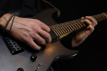 Fototapeta premium guitarist plays an electric guitar solo with a pick on black background