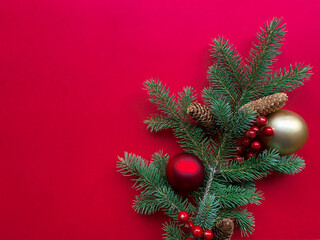 Fototapeta na wymiar Christmas tree branches with Christmas balls and pine cones on red background. Flat lay mock up with copy space.