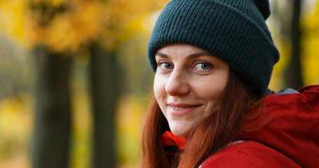 Young girl in warm clothes looks into the camera and smiles outside in cold weather after the rain. © Shi 