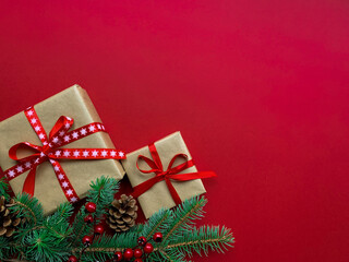 Christmas composition. Fat lay top view Christmas, New Year, holiday celebration red background with copy space. Template mock up design with gift, fir branches, pine cones and berries.
