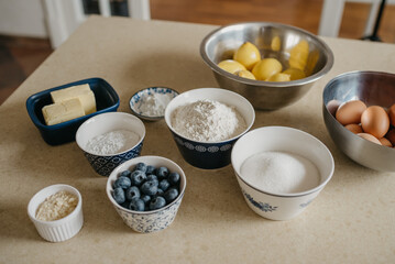 Obraz na płótnie Canvas Photo of eggs, lemons, two pieces of butter, blueberries, wheat flour, almond flour, sugar, powdered sugar, starch which are preparing for the lemon meringue tart in the kitchen.